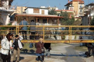 five people standing in an empty canal and two people standing on a metal bridge